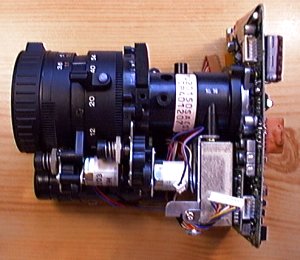 On aperçoit mieux l'objectif, les moteurs qui lui donnent vie, et sa fixation sur la platine CCD.